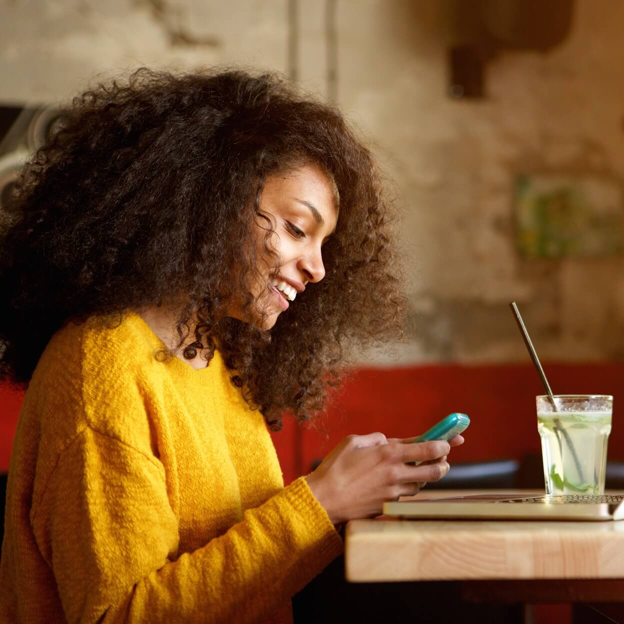 Woman in coffee shop with phone and laptop